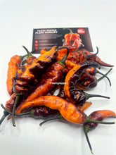 Load image into Gallery viewer, Black Panther peppers with a 'Tasty Pepper Plant Nursery' sign in the background.